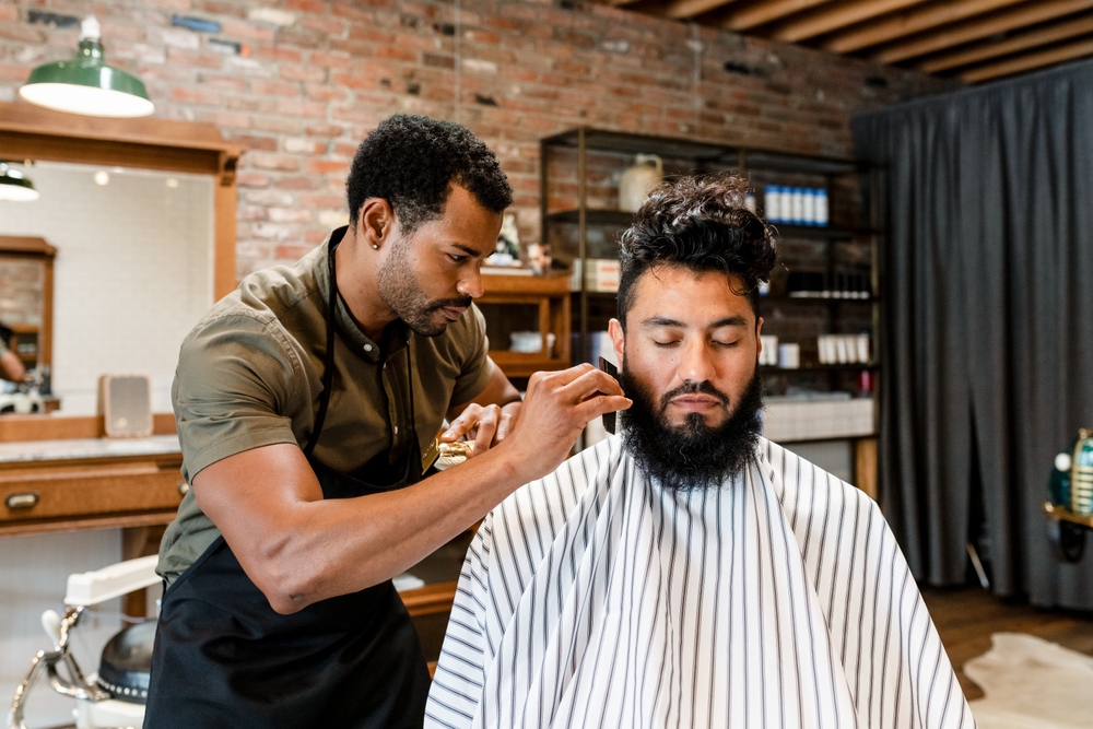 Hairdresser,trimming,beard,of,the,customer,at,a,barbershop,,small